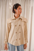 woman wearing fully buttoned trench coat whilst looking at the side
