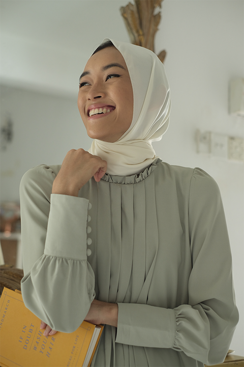 Female model smiling in high quality sage green dress by petit moi