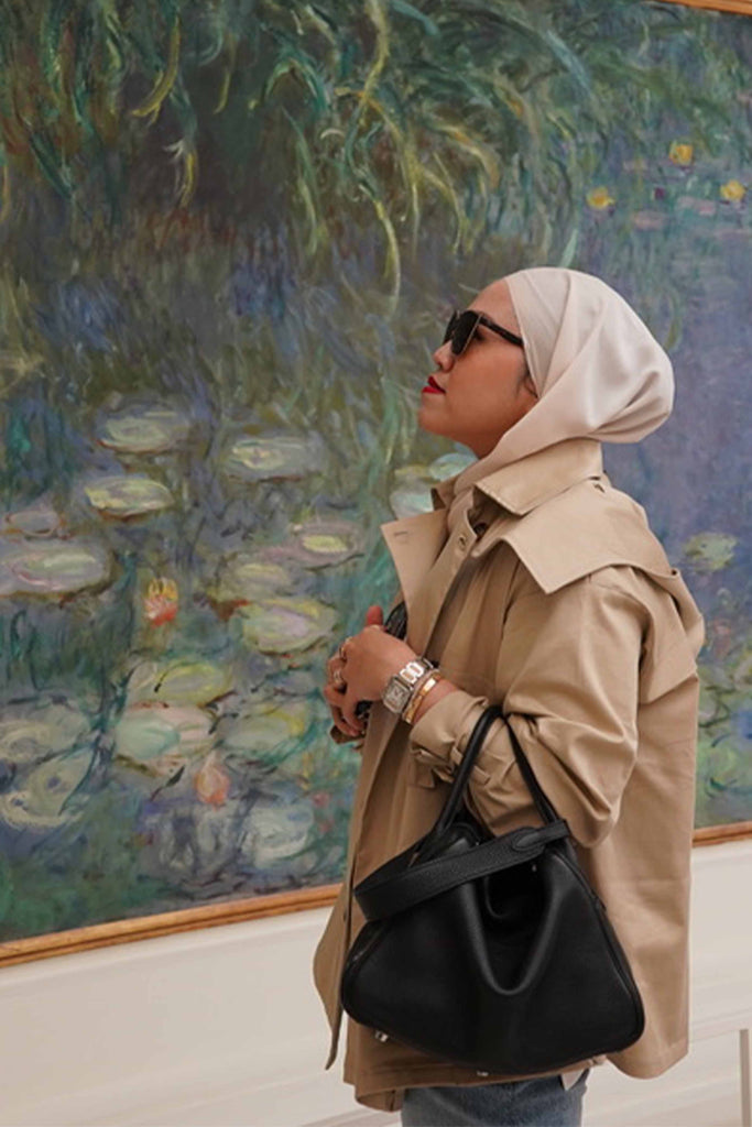 Female model admiring painting whilst wearing her favourite trench coat made by petit moi