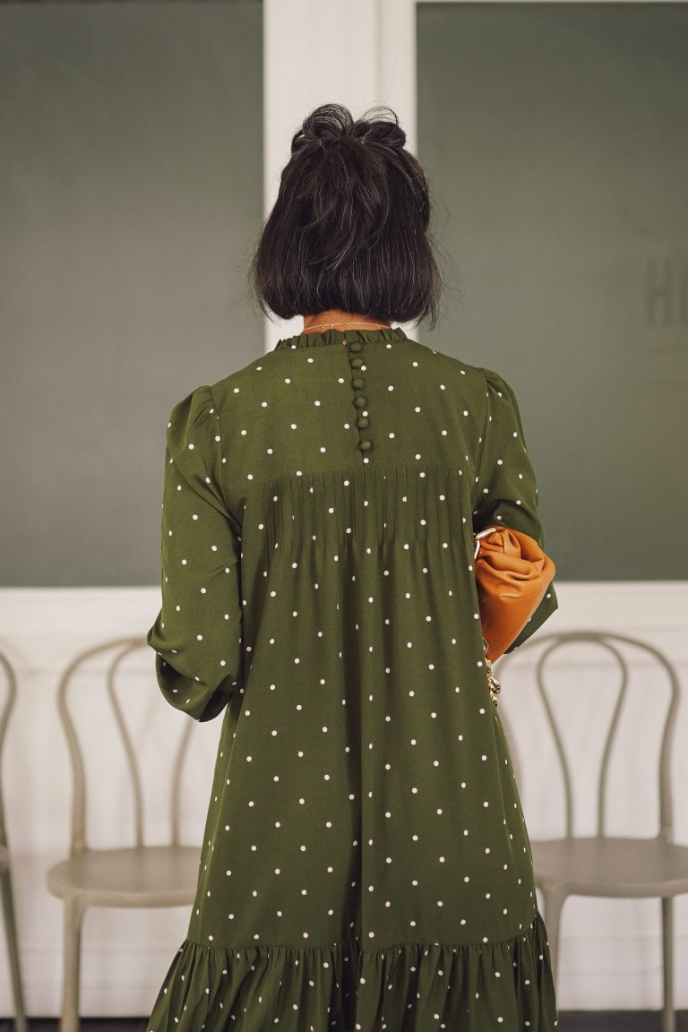 Closeup backshot of female model in high quality green polka dotted dress by petit moi