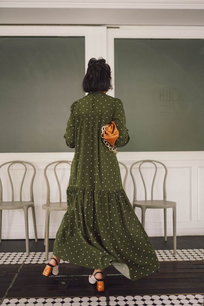 Back shot of female model in high quality green polka dress by petit moi