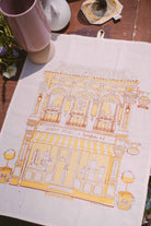 petit moi yellow bingka tea towel and cup on table